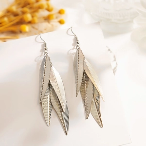Détail de feuilles argentées superposées sur des boucles d'oreilles vintage ajourées