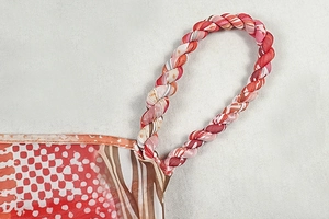 Detail of colorful printed dress showing woven rope straps and vibrant geometric pattern