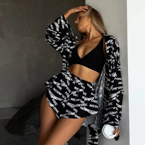 Detail of loose long-sleeved pajamas and high-waist shorts with all-over letter print