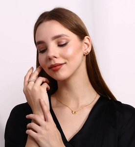 Close-up of golden ribbon bow necklace and earrings set worn by a fashion model