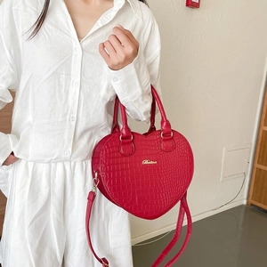 Rote herzförmige Handtasche mit Krokoprägung und goldenen Details am Modell