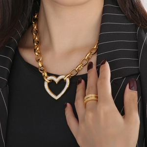 Close-up of gold chain necklace with iced-out heart pendant and matching ring on model
