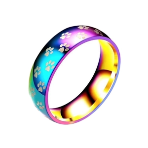 Makroansicht eines Regenbogenrings aus Titanstahl mit gravierten Pfotenabdruckmotiven.