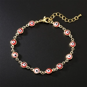 Golden chain bracelet with red evil eye beads on a black background, 80-100 characters.