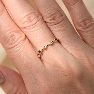 Close-up of golden slim ring with four gradient blue zircons on a person hand
