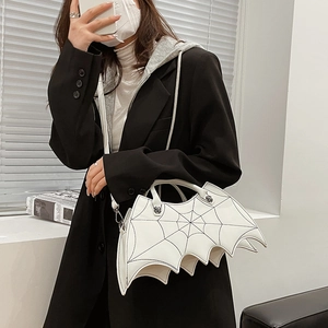 White bat-shaped shoulder bag with spider web embroidery detail worn by a model
