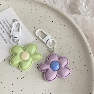Detail of colorful flower keychains with stitched petals and spring hooks on a ceramic tray