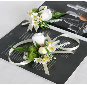 Detail of white rose boutonniere and wrist corsage set with satin ribbons on a magazine