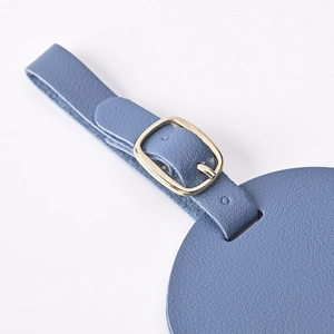 Detail of blue leather luggage tag with adjustable gold metal buckle for travel gear