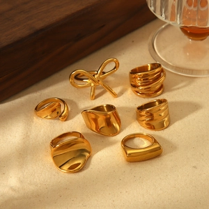 Set of gold irregular stainless steel rings with bow and minimalist designs on white linen