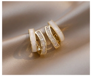 Details von goldenen Doppelreihen-Ohrringen mit Zirkonia-Steinen und weißem Emaille-Inlay