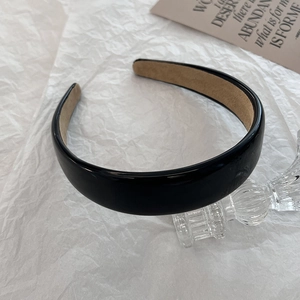 Detail of a wide black PU leather headband with comfortable beige fabric inner padding