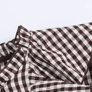 Macro shot of brown gingham fabric featuring detailed ruffle trim and textile texture