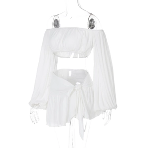 Dettaglio del crop top bianco a spalle scoperte e gonna a portafoglio con trama a pieghe