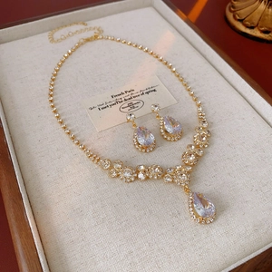 Détail de la parure en zircone avec collier doré et boucles d'oreilles goutte d'eau