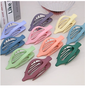 Flat lay of colorful matte leaf-shaped hair clips in various pastel tones on a surface