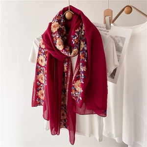 Ethnic style dark red summer shawl with floral embroidery hanging on wooden hanger