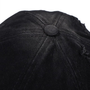 Detailed macro view of distressed cotton fabric and top button on a black baseball cap