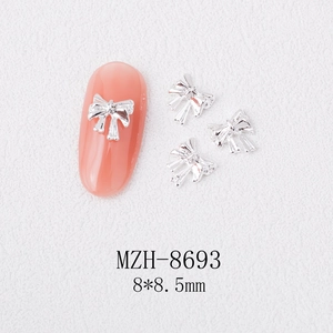 Macro detail of 8x8.5mm silver metal bow nail art jewelry charm showing embossed texture