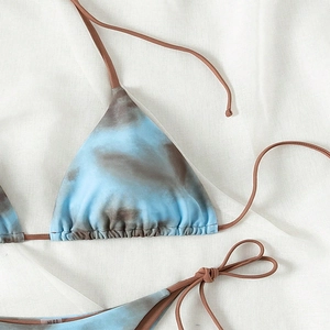 Close-up of lace-up bikini top featuring blue and grey tie-dye print and triangle cups
