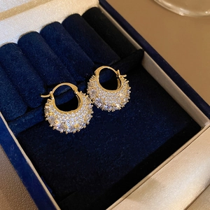 Close-up of gold-plated hoop earrings with micro-paved zircons in a navy velvet jewelry box