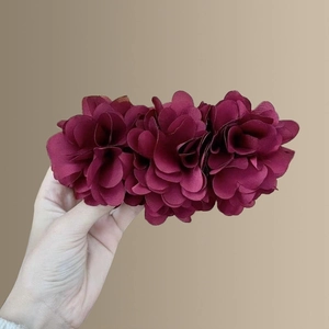 Close-up of three layered burgundy fabric flower hair clips with soft chiffon petals