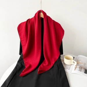 Detail of red cotton linen scarf draped with a magazine and mug on clean background