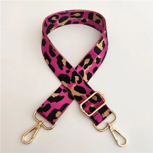 Close-up of adjustable leopard print nylon bag strap with polished gold-tone metal hooks