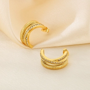 Boucles d'oreilles dorées en C avec texture spirale et strass sur fond de soie
