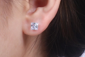Detailed close-up of a square-cut zircon stud earring with a four-prong silver setting