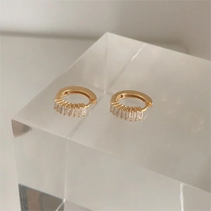 Macro shot of 925 silver gold huggie earrings featuring baguette cut square cubic zirconia