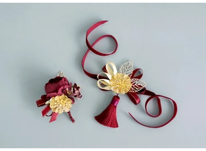 Macro detail of burgundy silk flower set with golden metal leaves and long red tassels