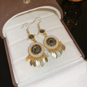 Detail of bohemian gold earrings with brown cat-eye stone and white pearls on velvet