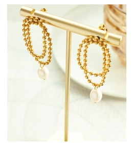 Detail of gold beaded hoop earrings with white freshwater pearl drops on a display stand
