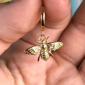 Detailed view of a gold-plated bee charm earring with intricate wing and body texture