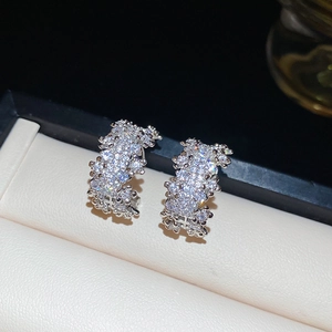 Detailed macro view of silver C-shaped earrings pavé-set with shimmering cubic zirconia