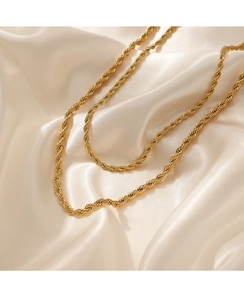 Detail view of a 4mm gold twist chain necklace resting on elegant beige silk fabric