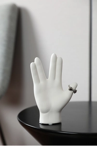 Close-up of matte white ceramic hand sculpture showing Vulcan salute jewelry display