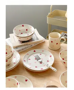 Detailed set of cream ceramic heart pattern plates, bowls and mug on a wooden table