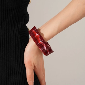 Detail of red wavy resin bangle with white cloud marble texture on a female wrist