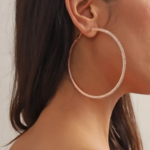 Close-up of oversized rose gold hoop earrings with sparkling rhinestones on a model