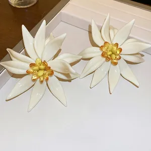 Exaggerated resin 3D flower earrings in cream white with colorful center beads on a jewelry tray