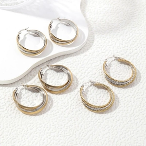 Three-pair layered hoop earrings set in gold and silver finish with textured steel surface