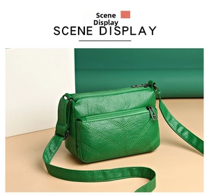 Detail of dark green soft leather crossbody bag featuring lychee texture and dual zippers