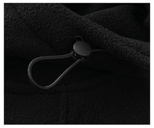 Macro detail of black fleece jacket showing adjustable drawstring toggle and fabric texture