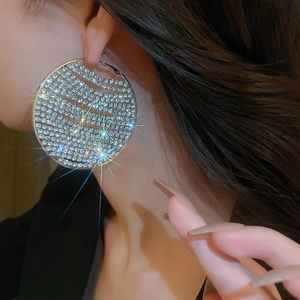 Close-up of luxury oversized silver hoop earrings with shimmering crystal wave pattern