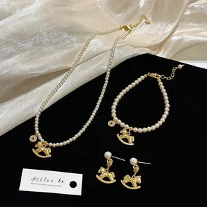 Détail d'une parure de bijoux en perles avec breloques de cheval à bascule doré