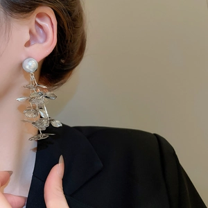Close-up of silver hollow floral tassel earring with pearl on model, showing elegant drape
