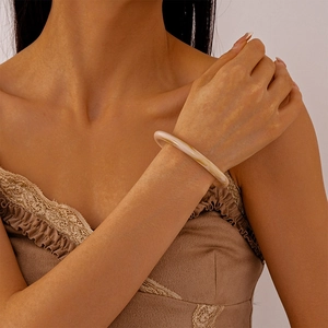 Close-up of a marbled cream acrylic bangle bracelet worn with a lace top for a chic look