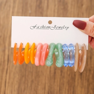 Macro shot of 5 pairs of acrylic C-shaped hoop earrings with unique textures on display card